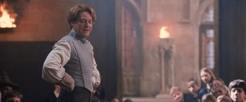 Movie still from “Harry Potter and the Chamber of Secrets” (2002), directed by Chris Columbus – A man in a gray jacket is standing in front of a fire; Medium shot, Over the shoulder angle