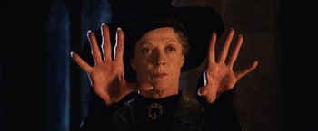 Movie still from “Harry Potter and the Chamber of Secrets” (2002), directed by Chris Columbus – An older woman wearing a black hat with her hands up; Close Up shot, Low angle