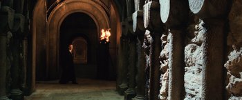 Movie still from “Harry Potter and the Chamber of Secrets” (2002), directed by Chris Columbus – A man standing next to a fire in a room; Wide shot, Over the shoulder angle