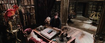 Movie still from “Harry Potter and the Chamber of Secrets” (2002), directed by Chris Columbus – A man sitting at a table in a room; Wide shot, High angle