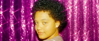 Movie still from “Asking for It” (2021), directed by Eamon O'Rourke – A young woman with short black hair in front of a purple background; Close Up shot, Low angle