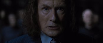 Movie still from “Harry Potter and the Deathly Hallows: Part 1” (2010), directed by David Yates – An old man with long hair wearing a suit and tie; Close Up shot, Over the shoulder angle