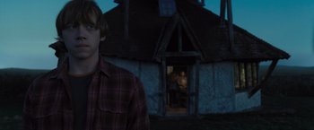 Movie still from “Harry Potter and the Deathly Hallows: Part 1” (2010), directed by David Yates – A man standing in front of a house at night; Medium shot, Over the shoulder angle