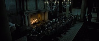 Movie still from “Harry Potter and the Deathly Hallows: Part 1” (2010), directed by David Yates – People sitting in front of a fireplace in a dark room; Wide shot, High angle