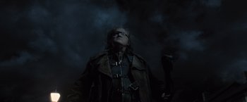 Movie still from “Harry Potter and the Deathly Hallows: Part 1” (2010), directed by David Yates – A man in a leather jacket looking up at the sky; Medium shot, Low angle