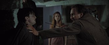 Movie still from “Harry Potter and the Deathly Hallows: Part 1” (2010), directed by David Yates – A man holding a wand in front of two women; Medium shot, Over the shoulder angle