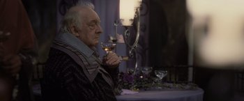 Movie still from “Harry Potter and the Deathly Hallows: Part 1” (2010), directed by David Yates – An older man holding a glass of wine; Medium shot, Over the shoulder angle