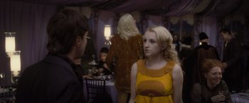 Movie still from “Harry Potter and the Deathly Hallows: Part 1” (2010), directed by David Yates – A woman in a yellow and brown dress in front of people; Medium shot, Over the shoulder angle
