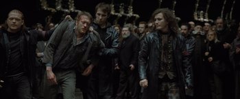 Movie still from “Harry Potter and the Deathly Hallows: Part 1” (2010), directed by David Yates – A group of men in leather jackets walking down a street; Medium shot, Over the shoulder angle