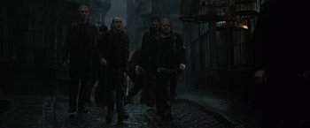 Movie still from “Harry Potter and the Deathly Hallows: Part 1” (2010), directed by David Yates – A group of people walking down a street in the dark; Wide shot, Low angle