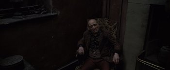 Movie still from “Harry Potter and the Deathly Hallows: Part 1” (2010), directed by David Yates – A man sitting in a chair with his eyes closed; Medium shot, High angle