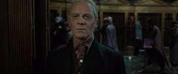 Movie still from “Harry Potter and the Deathly Hallows: Part 1” (2010), directed by David Yates – An older man in a suit and tie in front of a building; Close Up shot, Low angle