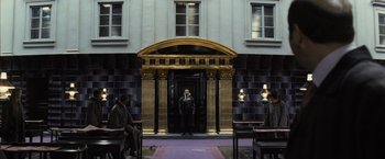 Movie still from “Harry Potter and the Deathly Hallows: Part 1” (2010), directed by David Yates – A man standing in front of an entrance to a building; Wide shot, Low angle