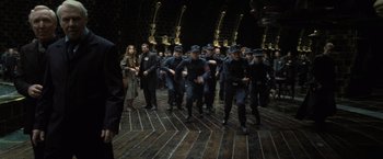 Movie still from “Harry Potter and the Deathly Hallows: Part 1” (2010), directed by David Yates – A group of men in black uniforms are marching; Wide shot, High angle