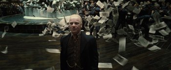 Movie still from “Harry Potter and the Deathly Hallows: Part 1” (2010), directed by David Yates – A man standing in front of a bunch of newspapers; Medium shot, Low angle