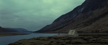 Movie still from “Harry Potter and the Deathly Hallows: Part 1” (2010), directed by David Yates – A person standing next to a tent near a body of water; Extreme Wide shot, High angle