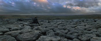 Movie still from “Harry Potter and the Deathly Hallows: Part 1” (2010), directed by David Yates – A person sitting on top of a large rock formation; Extreme Wide shot, High angle