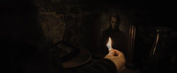 Movie still from “Harry Potter and the Deathly Hallows: Part 1” (2010), directed by David Yates – A person is holding a candle in front of a picture of a man; Close Up shot, Over the shoulder angle