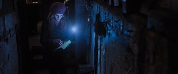 Movie still from “Harry Potter and the Deathly Hallows: Part 1” (2010), directed by David Yates – A woman is reading a book in the dark with a flashlight; Medium shot, Low angle