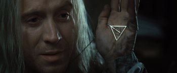 Movie still from “Harry Potter and the Deathly Hallows: Part 1” (2010), directed by David Yates – A person holding a necklace with a triangle on it; Close Up shot, Overhead angle