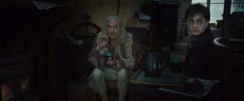 Movie still from “Harry Potter and the Deathly Hallows: Part 1” (2010), directed by David Yates – An old man sitting in a chair holding a phone; Medium shot, Low angle