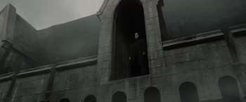 Movie still from “Harry Potter and the Deathly Hallows: Part 2” (2011), directed by David Yates – A man in a black robe standing inside a building; Wide shot, Low angle