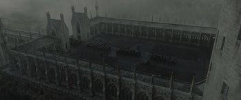 Movie still from “Harry Potter and the Deathly Hallows: Part 2” (2011), directed by David Yates – A group of people sitting in a row in front of a building; Extreme Wide shot, High angle