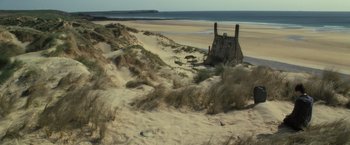 Movie still from “Harry Potter and the Deathly Hallows: Part 2” (2011), directed by David Yates – An old building on the beach with a view of the ocean; Extreme Wide shot, High angle