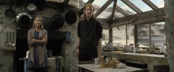 Movie still from “Harry Potter and the Deathly Hallows: Part 2” (2011), directed by David Yates – A man standing in a kitchen next to a table; Medium shot, Low angle