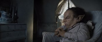 Movie still from “Harry Potter and the Deathly Hallows: Part 2” (2011), directed by David Yates – An old man sitting on a couch with his eyes closed; Close Up shot, High angle
