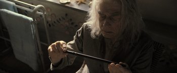Movie still from “Harry Potter and the Deathly Hallows: Part 2” (2011), directed by David Yates – An older man holding a wooden stick in his hands; Close Up shot, High angle