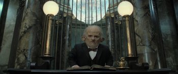 Movie still from “Harry Potter and the Deathly Hallows: Part 2” (2011), directed by David Yates – An old man is reading a book in a room; Medium shot, Low angle