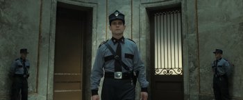 Movie still from “Harry Potter and the Deathly Hallows: Part 2” (2011), directed by David Yates – A man in a uniform standing in front of a door way; Medium shot, Low angle