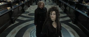 Movie still from “Harry Potter and the Deathly Hallows: Part 2” (2011), directed by David Yates – A woman in a long black dress standing next to a man in a long black coat; Medium shot, Over the shoulder angle