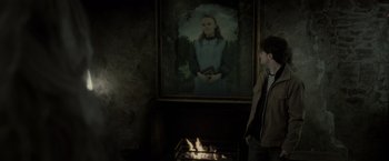 Movie still from “Harry Potter and the Deathly Hallows: Part 2” (2011), directed by David Yates – A man standing in front of a fireplace next to a painting; Medium shot, Over the shoulder angle