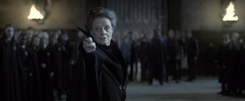 Movie still from “Harry Potter and the Deathly Hallows: Part 2” (2011), directed by David Yates – An older woman holding a knife in front of a group of people; Close Up shot, Over the shoulder angle