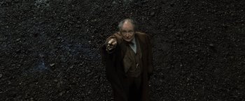 Movie still from “Harry Potter and the Deathly Hallows: Part 2” (2011), directed by David Yates – An old man in a brown coat pointing at the camera; Medium shot, Overhead angle