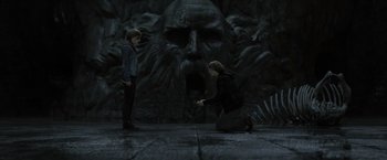 Movie still from “Harry Potter and the Deathly Hallows: Part 2” (2011), directed by David Yates – Two people are standing in front of a stone face; Wide shot, High angle