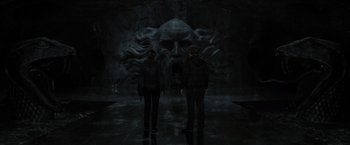 Movie still from “Harry Potter and the Deathly Hallows: Part 2” (2011), directed by David Yates – Two people are standing in front of a statue of a face; Wide shot, Low angle