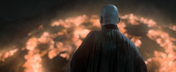 Movie still from “Harry Potter and the Deathly Hallows: Part 2” (2011), directed by David Yates – A bald man wearing a black cape looking at the sky; Medium shot, Over the shoulder angle