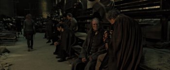 Movie still from “Harry Potter and the Deathly Hallows: Part 2” (2011), directed by David Yates – A group of people sitting on a bench in a room; Medium shot, High angle