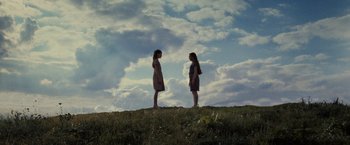 Movie still from “Harry Potter and the Deathly Hallows: Part 2” (2011), directed by David Yates – Two young girls standing on top of a grassy hill looking at each other; Wide shot, Low angle