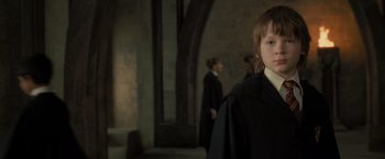 Movie still from “Harry Potter and the Deathly Hallows: Part 2” (2011), directed by David Yates – A young boy in a black robe stands in front of two other young people; Close Up shot, Low angle