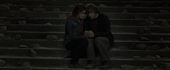 Movie still from “Harry Potter and the Deathly Hallows: Part 2” (2011), directed by David Yates – A couple of people that are sitting on some steps; Medium shot, High angle
