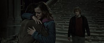Movie still from “Harry Potter and the Deathly Hallows: Part 2” (2011), directed by David Yates – A woman hugging a man in front of some stairs; Medium shot, Low angle