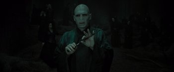 Movie still from “Harry Potter and the Deathly Hallows: Part 2” (2011), directed by David Yates – A man with a bald head holding a magic wand; Medium shot, High angle