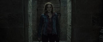 Movie still from “Harry Potter and the Deathly Hallows: Part 2” (2011), directed by David Yates – A woman standing in a dark room holding a bag; Medium shot, Low angle
