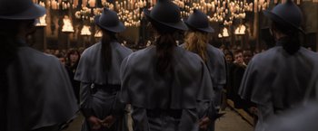 Movie still from “Harry Potter and the Goblet of Fire” (2005), directed by Mike Newell – A group of women wearing hats standing next to each other in front of lights; Medium shot, Low angle
