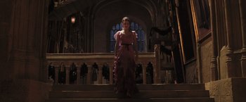 Movie still from “Harry Potter and the Goblet of Fire” (2005), directed by Mike Newell – A woman in a pink dress standing on steps in front of a building; Wide shot, Low angle