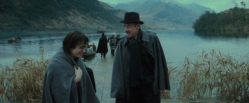 Movie still from “Harry Potter and the Goblet of Fire” (2005), directed by Mike Newell – A man wearing a hat and a coat walking by a body of water; Medium shot, Over the shoulder angle